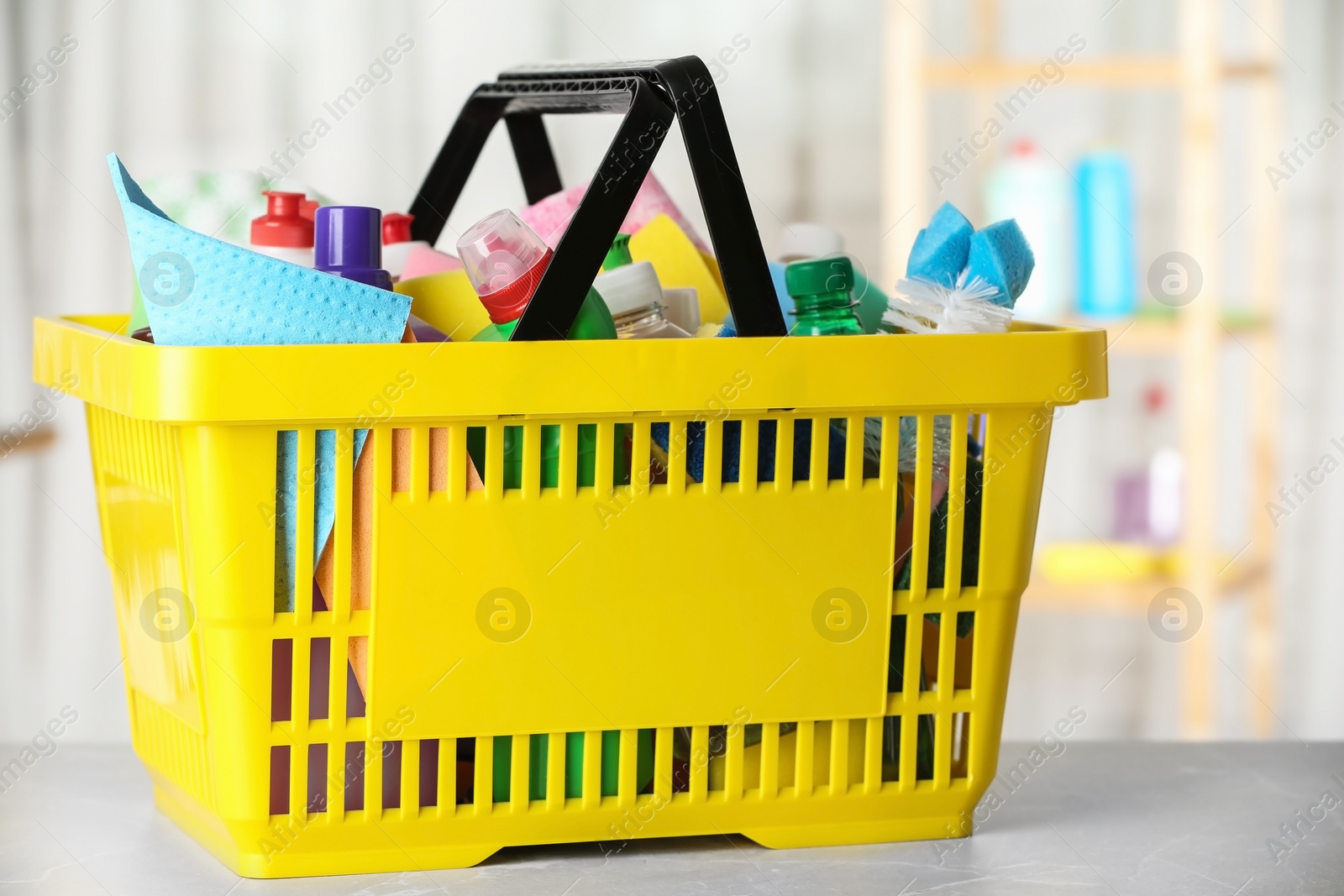 Photo of Shopping basket with different detergents on light marble table indoors