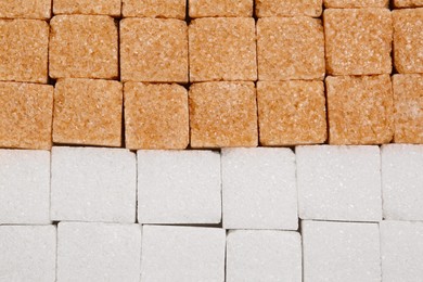 White and brown refined sugar cubes as background, top view