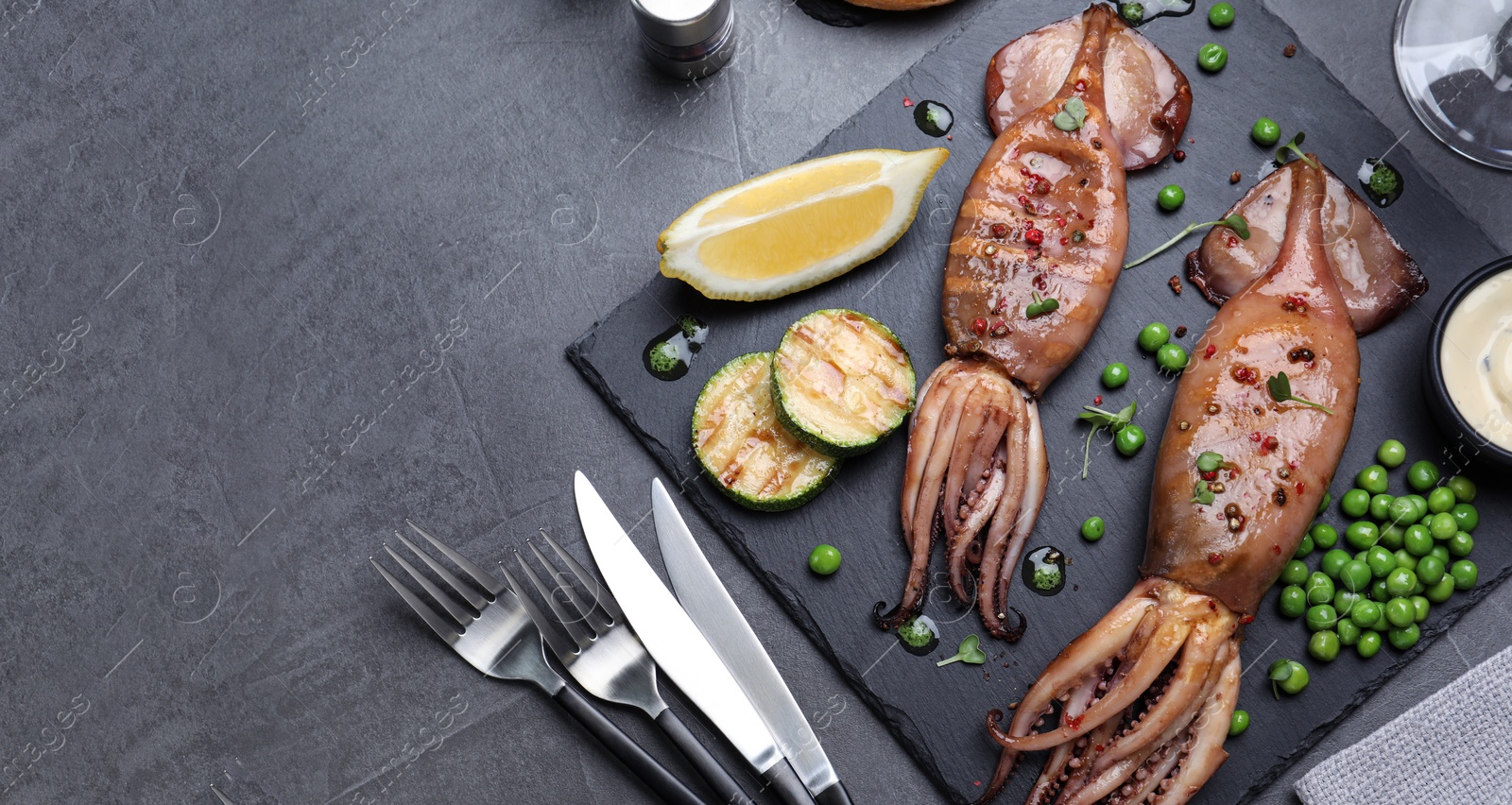 Image of Tasty grilled squids served on grey table, flat lay. Banner design with space for text