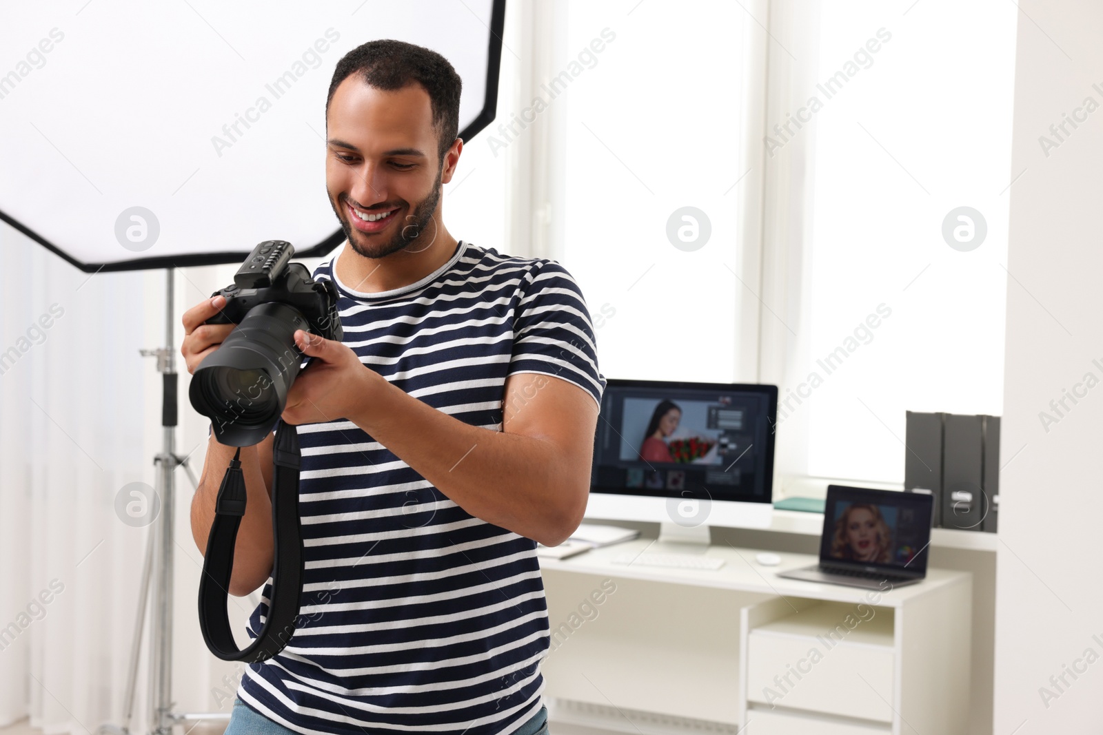 Photo of Young professional photographer with camera in modern photo studio, space for text