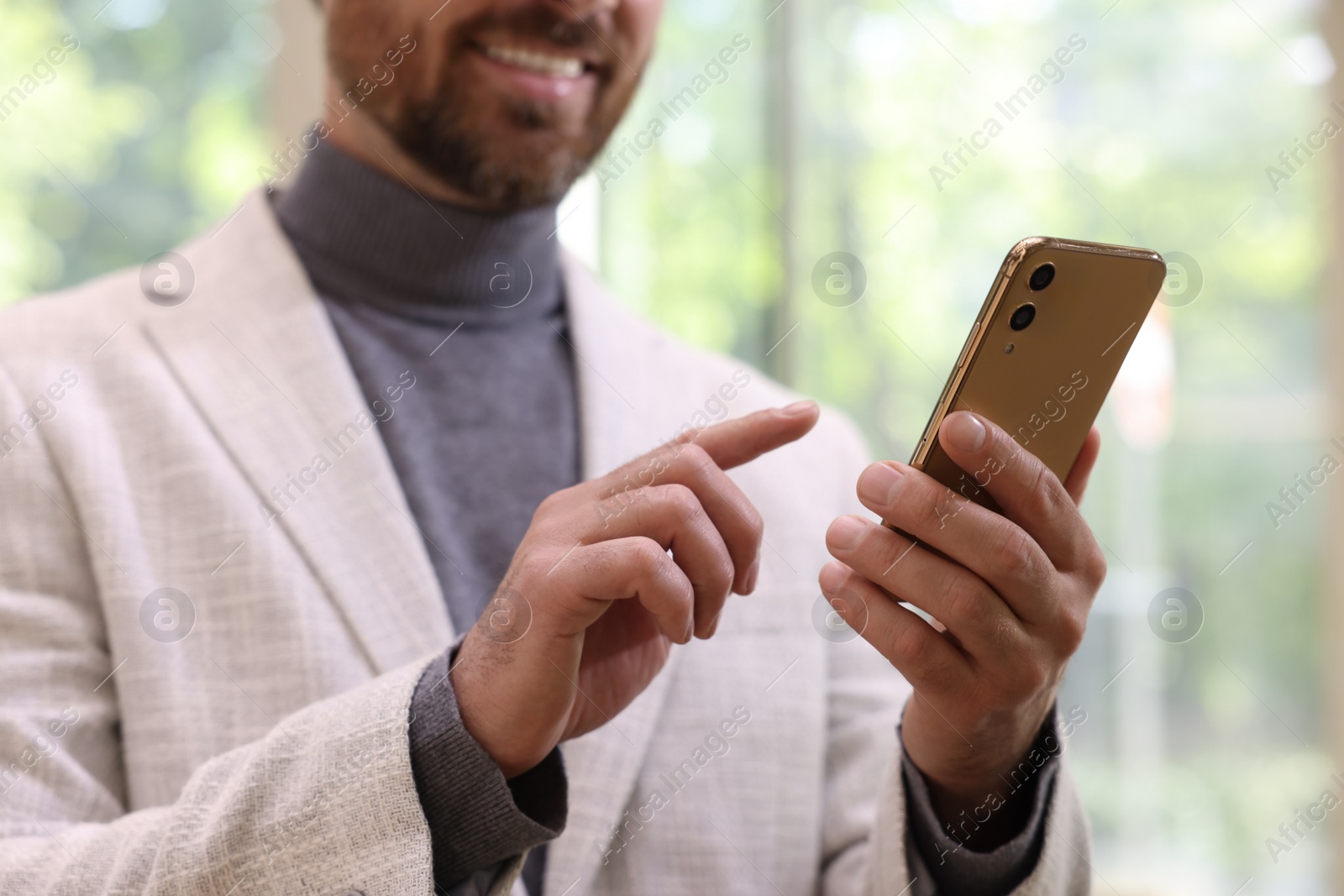 Photo of Man sending message via smartphone indoors, closeup