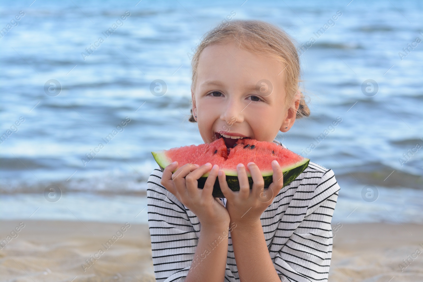 Photo of Cute little girl eating fresh juicy watermelon on beach