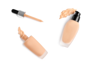 Photo of Bottles of liquid foundation and dropper on white background, top view