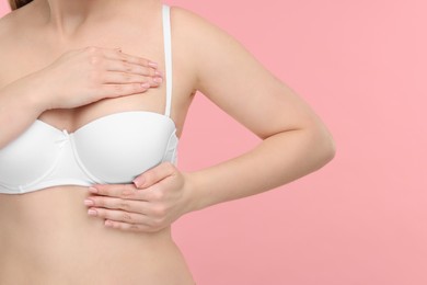 Photo of Mammology. Young woman doing breast self-examination on pink background, closeup