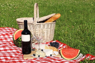 Picnic blanket with delicious food and wine outdoors on summer day