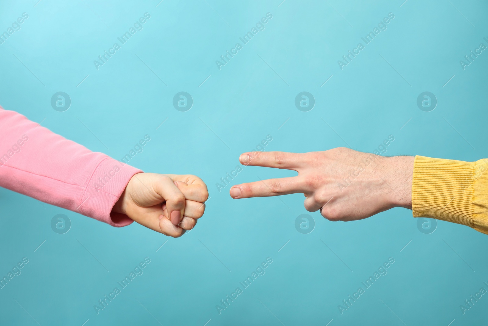 Photo of People playing rock, paper and scissors on light blue background, closeup