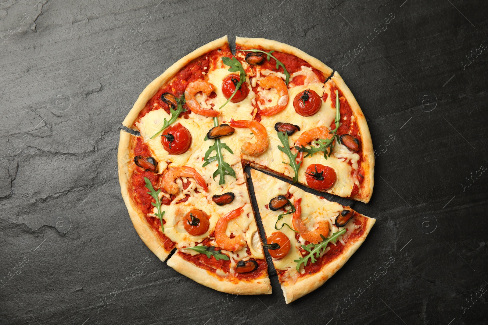 Photo of Delicious seafood pizza on black table, top view