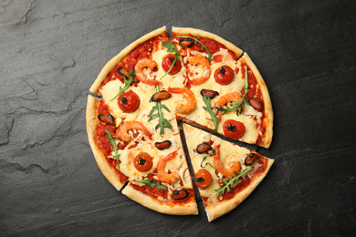 Photo of Delicious seafood pizza on black table, top view