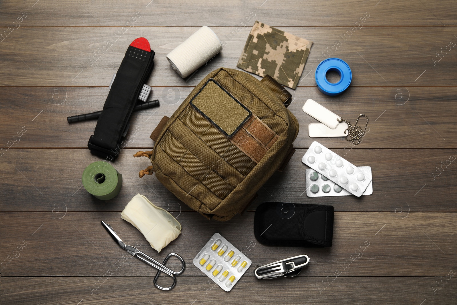 Photo of Military first aid kit on wooden table, flat lay