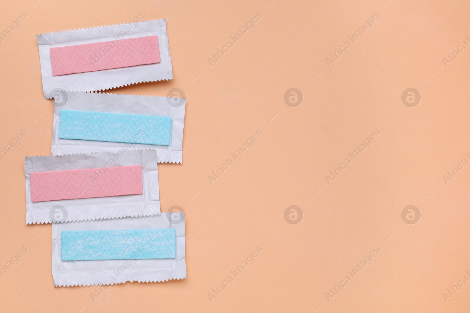 Photo of Unwrapped sticks of chewing gum on coral background, flat lay. Space for text