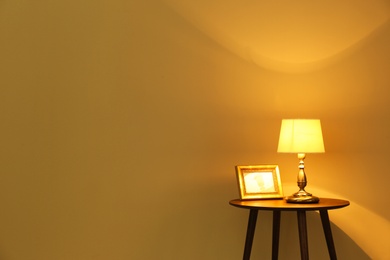 Modern lamp on table against color background. Space for text