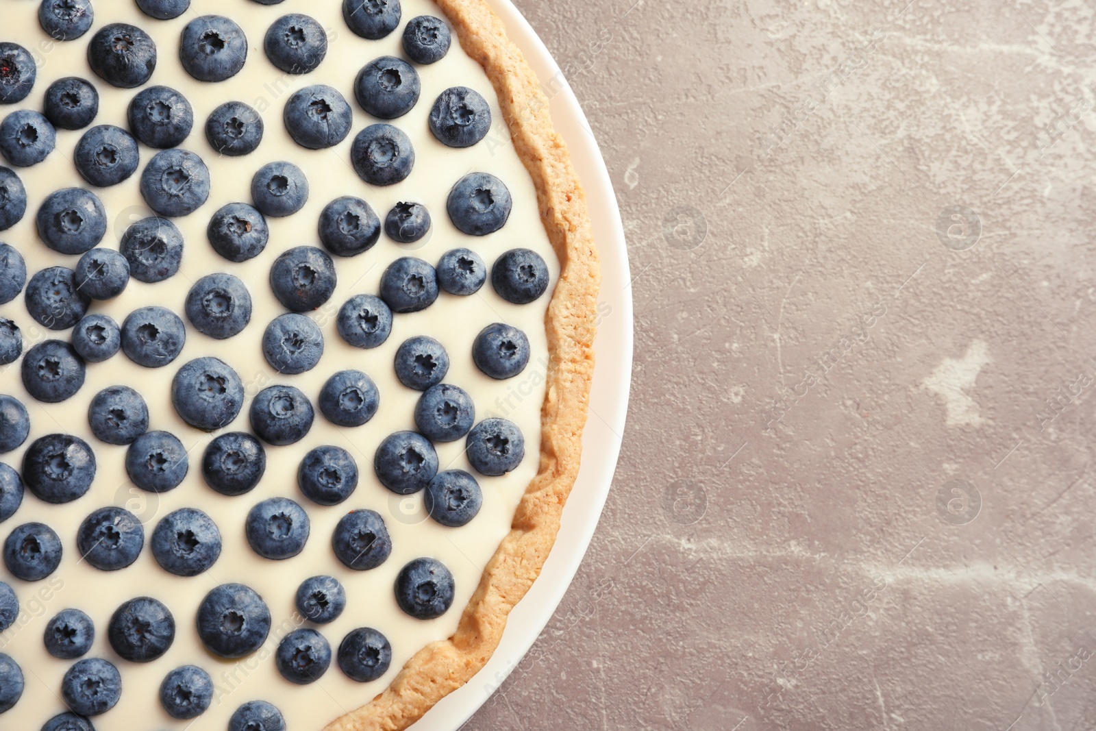 Photo of Tasty blueberry cake on gray background, top view with space for text