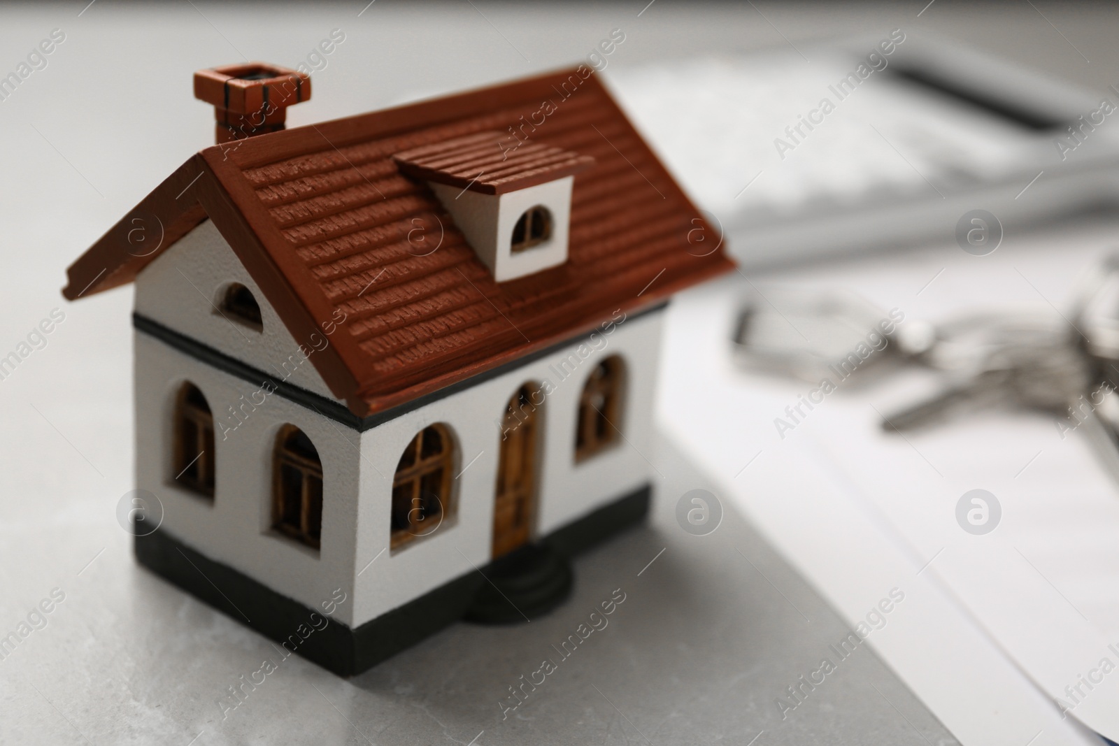 Photo of House model with documents on table, closeup. Real estate agent service