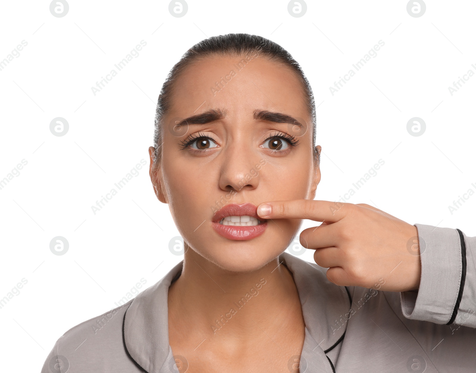 Photo of Emotional woman with herpes touching lips on white background