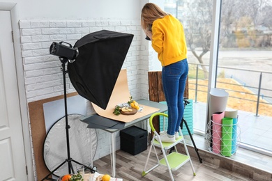 Photo of Young woman taking picture of lemons, mint and ginger in professional studio. Food photography