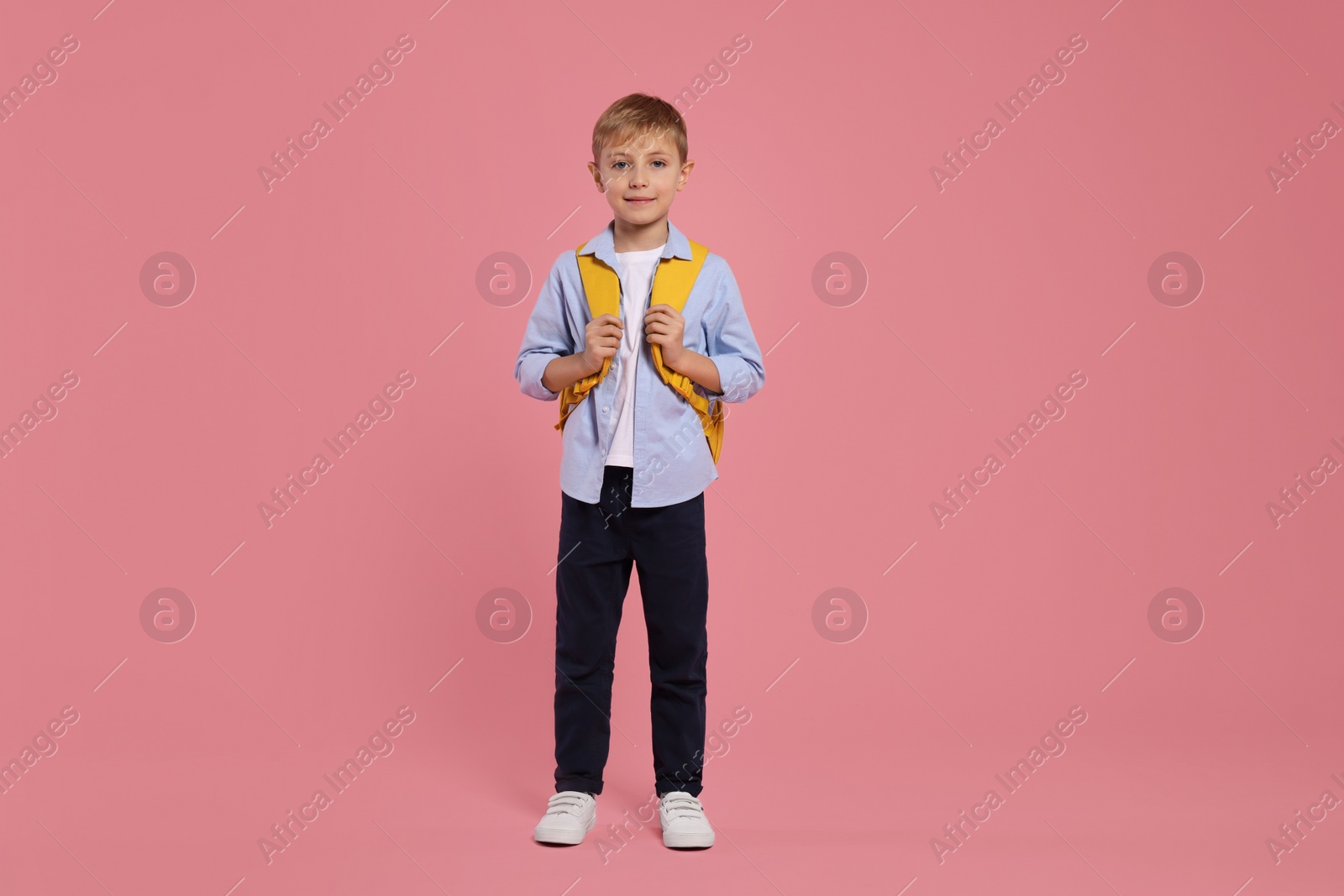 Photo of Happy schoolboy with backpack on pink background