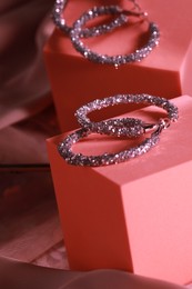 Photo of Elegant jewelry. Stylish presentation of luxury earrings on podium near mirror, closeup