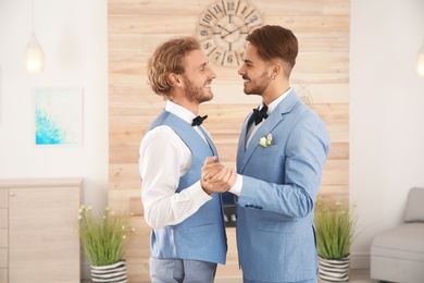 Happy newlywed gay couple dancing at home