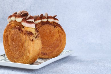 Photo of Tasty puff pastry. Supreme croissants with chocolate chips and cream on grey background, closeup. Space for text