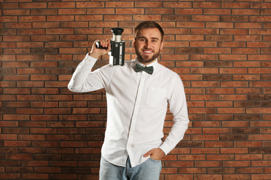 Photo of Young man with vintage video camera near brick wall