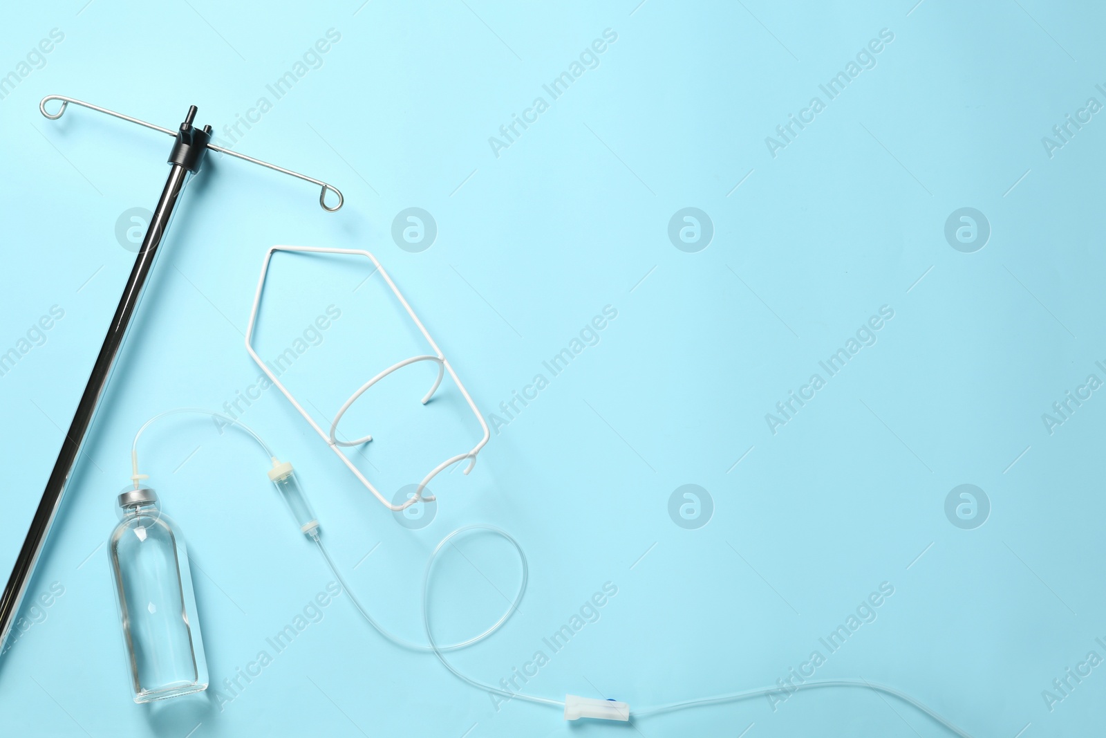 Photo of IV infusion set on light blue background, flat lay. Space for text