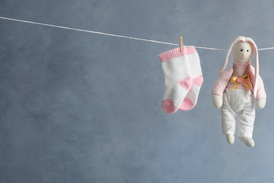 Pair of child's socks and toy bunny hanging on laundry line against dark background, space for text
