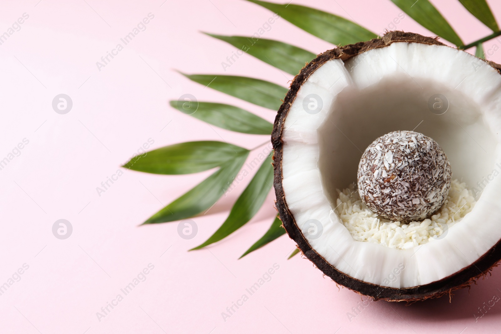 Photo of Composition with delicious vegan candy ball and coconut on pink background. Space for text