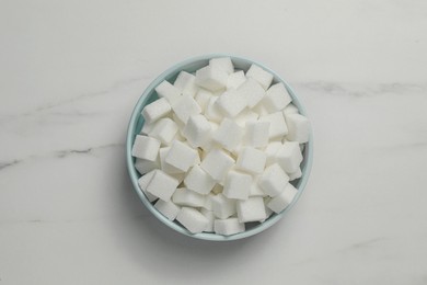 Bowl of white sugar cubes on marble table, top view