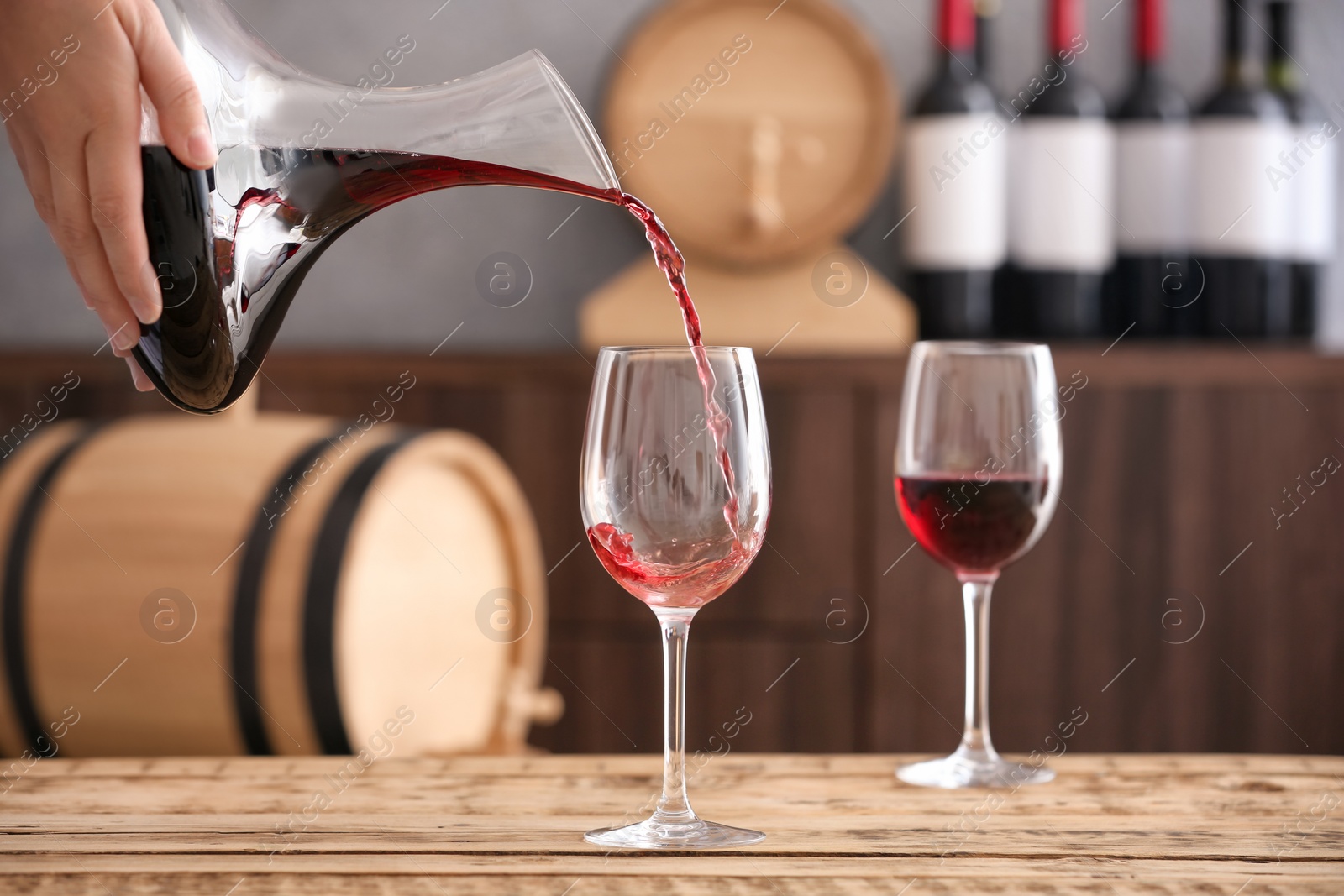 Photo of Pouring delicious red wine into glass on table