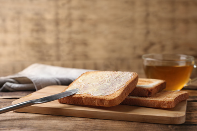 Photo of Delicious crispy toasts with butter on wooden table