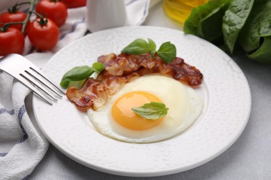 Photo of Fried egg and bacon served on light grey table