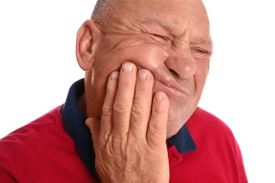 Mature man suffering from toothache on white background, closeup