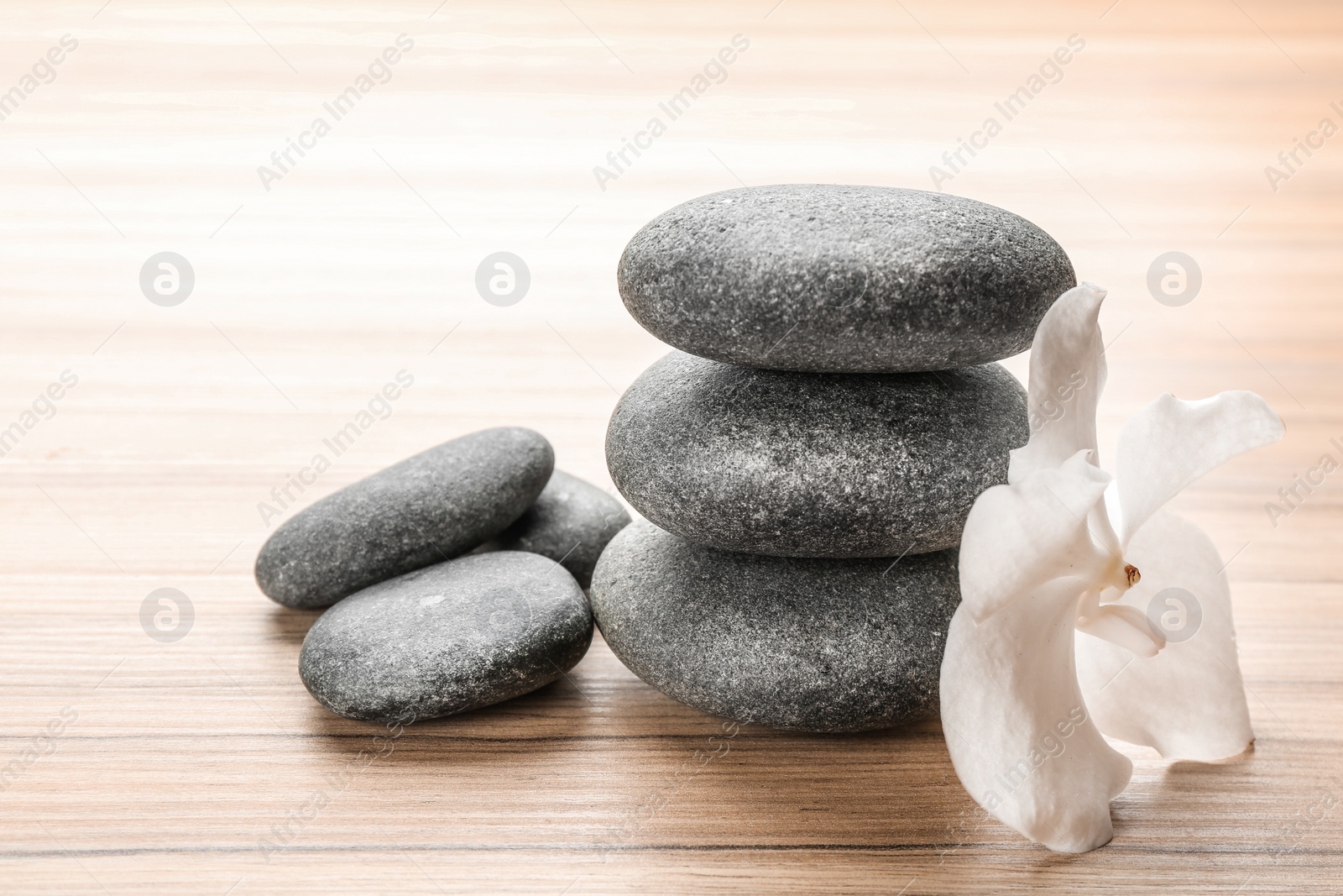 Photo of Stones and orchid flower on wooden background. Zen lifestyle