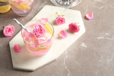 Delicious refreshing drink with lemon and roses on marble table, above view