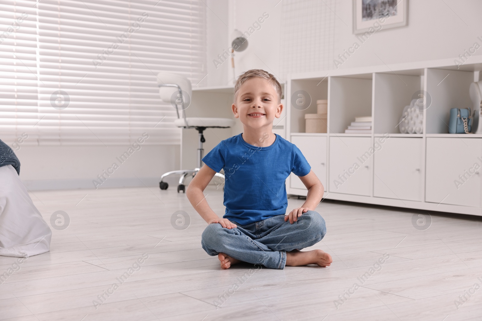 Photo of Cute little boy sitting on warm floor at home. Heating system