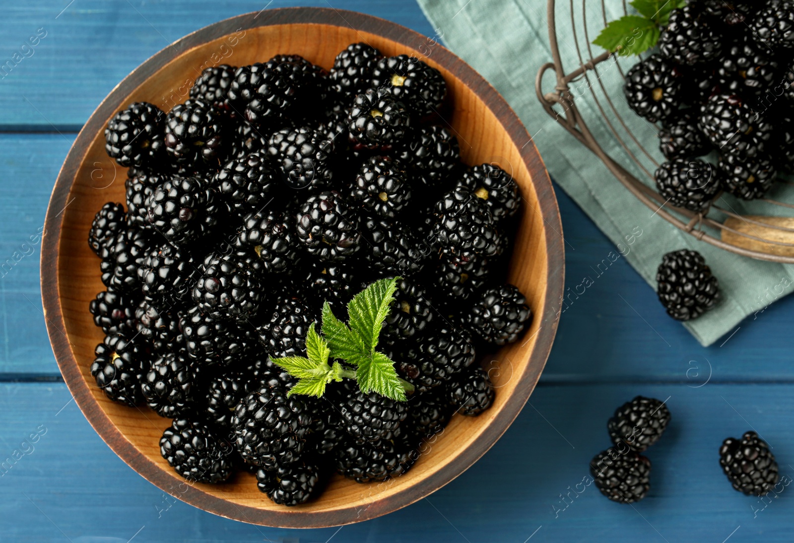 Photo of Fresh ripe blackberries on blue wooden table, flat lay