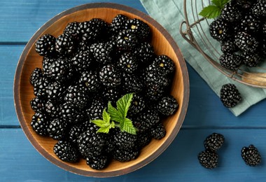 Photo of Fresh ripe blackberries on blue wooden table, flat lay