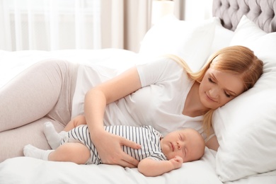 Mother with her baby resting on bed at home