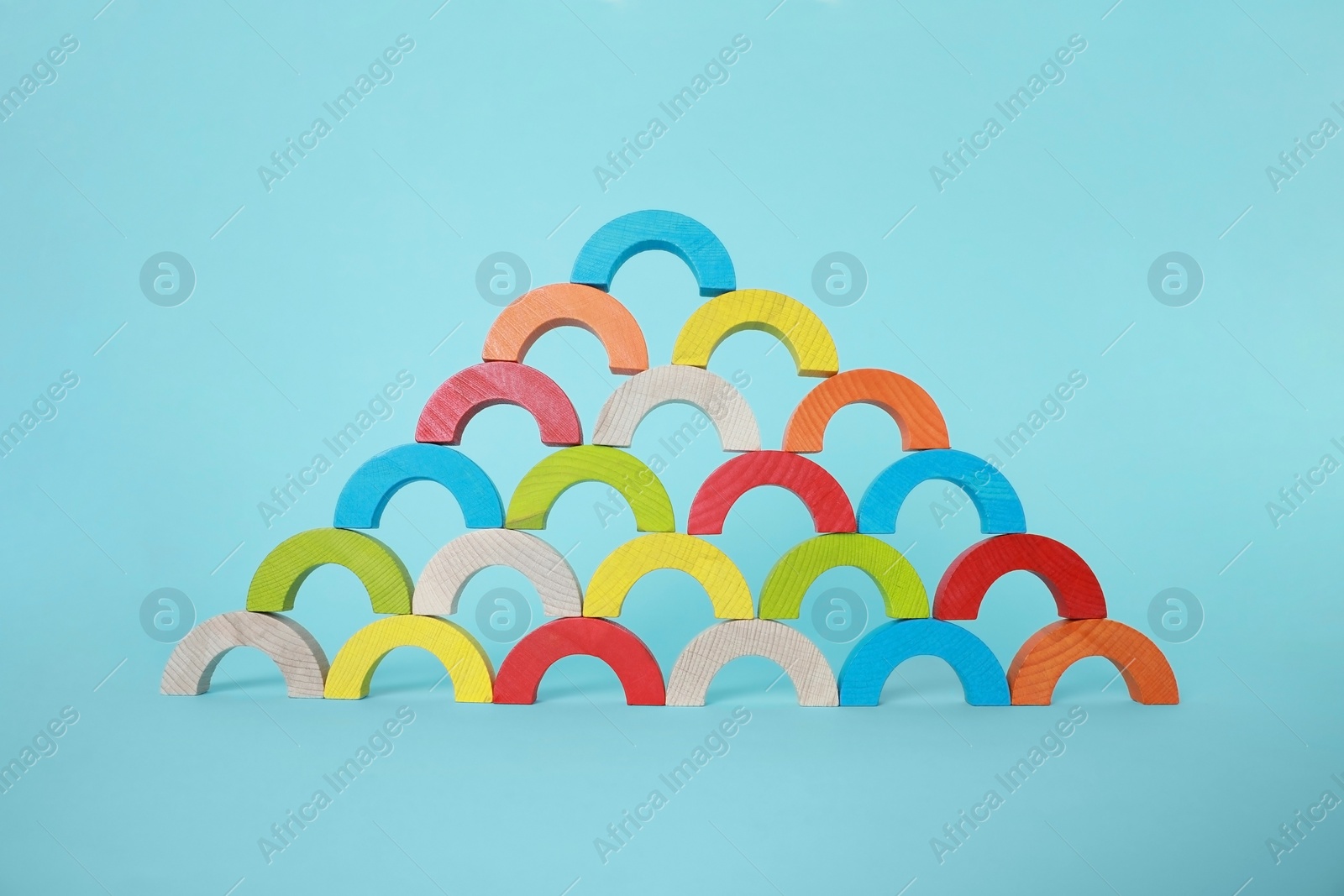 Photo of Colorful wooden pieces of playing set on light blue background. Educational toy for motor skills development