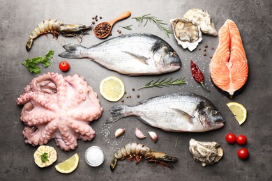 Flat lay composition with fresh raw dorado fish and different seafood on grey table