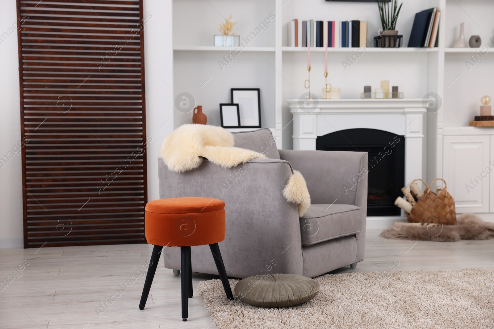 Photo of Comfortable armchair, fireplace and shelves in living room. Interior design
