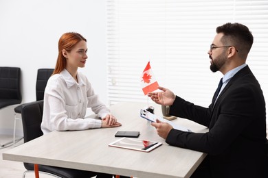 Smiling embassy worker consulting woman about immigration to Canada in office