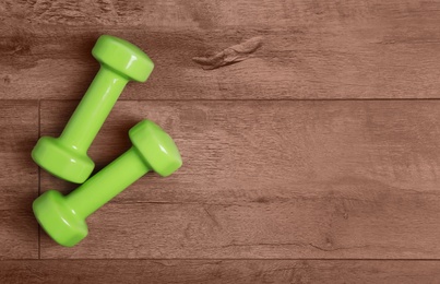 Vinyl dumbbells and space for text on wooden background, flat lay