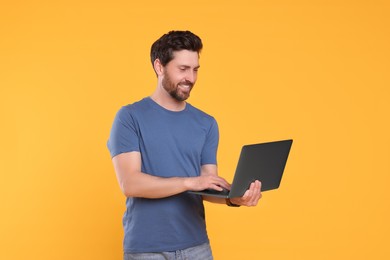 Happy man with laptop on yellow background