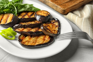 Plate with fried eggplant slices on table, closeup