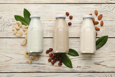Photo of Different vegan milks and nuts on white wooden table, flat lay