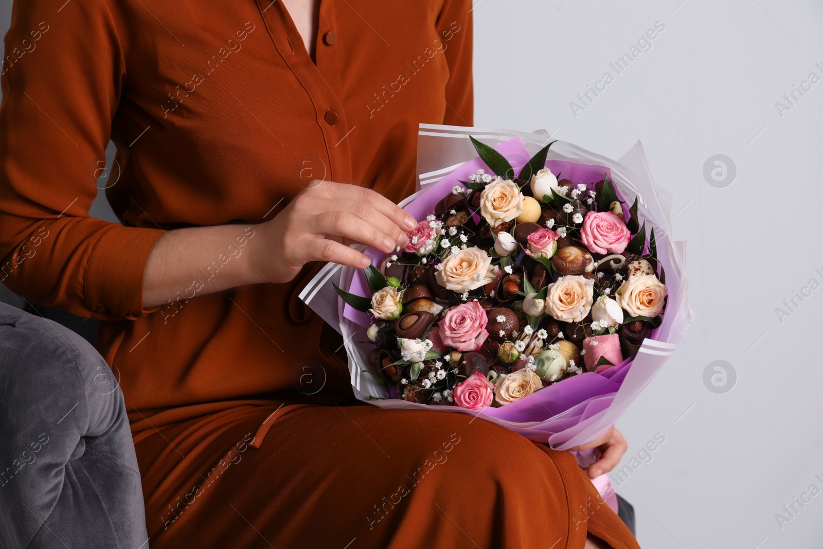 Photo of Woman with beautiful food bouquet on light grey background, closeup