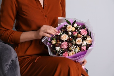 Photo of Woman with beautiful food bouquet on light grey background, closeup