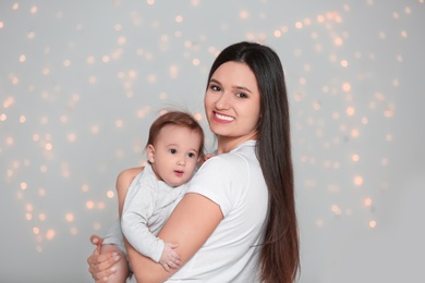 Portrait of young mother and her adorable baby against defocused lights