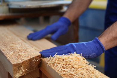 Photo of Professional carpenter working with wood in shop, closeup